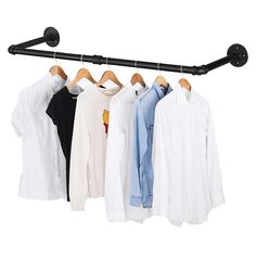 three shirts hanging on a rail and one is white