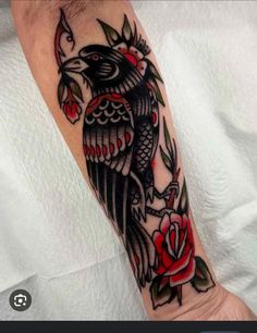 a black bird with red roses on it's arm is shown in this image