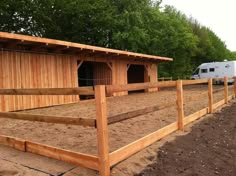 a horse pen with two stalls and a trailer in the backgroung area