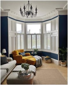 a living room filled with furniture and a chandelier hanging from the ceiling over a window