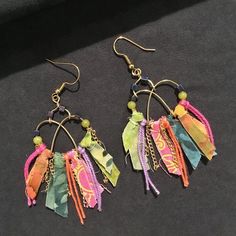 two pairs of multicolored paper earrings on black fabric with gold - plated earwires