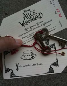 someone is holding up a ticket for alice and the wonderland tea party with a pair of old keys attached to it