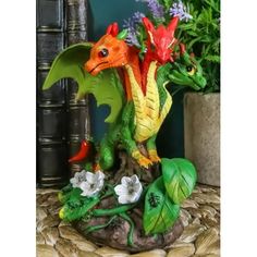 a dragon figurine sitting on top of a table next to flowers and plants