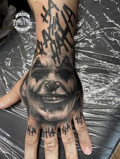 a man's hand with an evil face tattooed on it