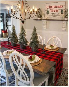 a dining room table decorated for christmas with pine trees on the top and plaid runner