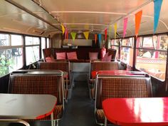 the inside of a bus with tables, chairs and bunting streamers hanging from the ceiling