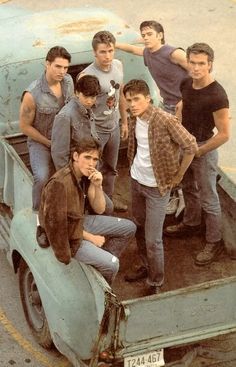 a group of young men standing in the back of a truck