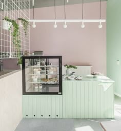 the interior of a restaurant with pink walls and green accents, along with an open counter