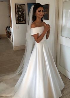 a woman in a white wedding dress standing next to a doorway with a veil on her head