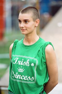 a young man wearing a green shirt and standing on the street with his hands in his pockets