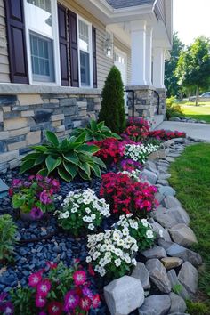 some flowers and rocks in front of a house