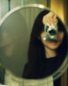 a woman holding a camera in front of a mirror