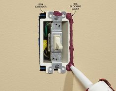 an electrical outlet with wiring attached to it and labeled on the wall behind it,