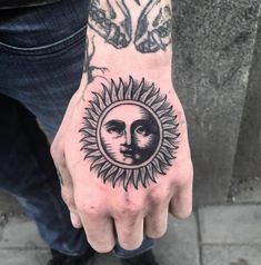 a hand with a sun and moon tattoo on it