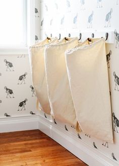 three bags hanging from the side of a wall in a room with black and white wallpaper