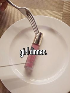 a fork sticking out of a white plate with the words girl dinner on it next to a pink lip