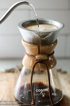 a coffee pot filled with liquid on top of a wooden table