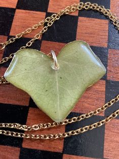 a green heart shaped glass pendant on a gold plated chain necklace with an attached clasp