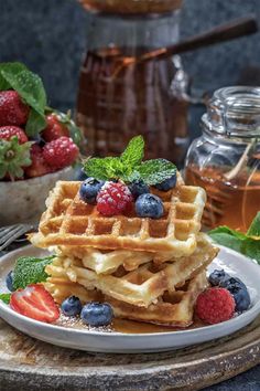 a stack of waffles topped with berries and mint