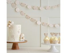 two cupcakes are sitting on a cake stand next to a birthday cake and bunting