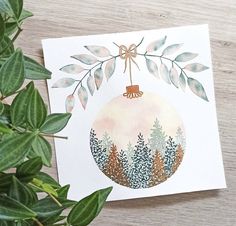 a christmas ornament is hanging from a tree branch with leaves around it on a card