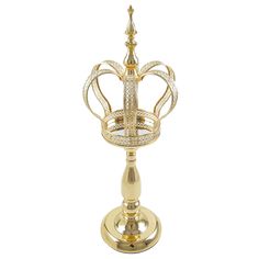 a gold and white candle holder with a crown on it's top, sitting on a stand