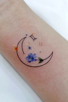 a small tattoo on the arm of a woman with flowers and stars around it's edges