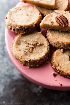 a pink plate topped with cookies and pecans