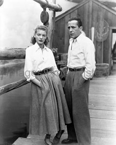 an old black and white photo of two people standing next to each other on a boat