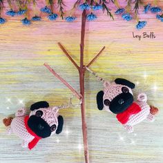 two small stuffed animals hanging from hooks on a tree branch