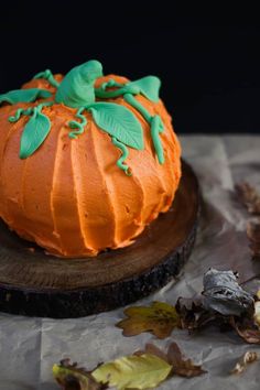 a pumpkin cake sitting on top of a wooden table next to leaves and other decorations