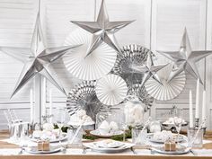 a table topped with silver star decorations and plates