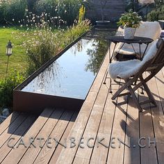 a chair sitting on top of a wooden deck next to a small pond and garden