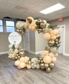 a balloon arch in the shape of a letter with gold and white balloons on it