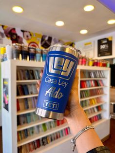 a person holding up a can in front of a book shelf