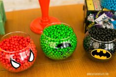 three plastic cups filled with candy sitting on top of a wooden table next to each other