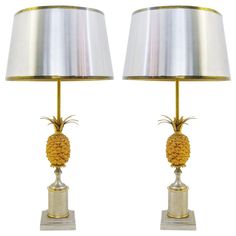 pair of brass pineapple table lamps with shades on each one side and a silver metal base