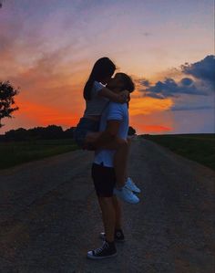 a man carrying a woman on his back as the sun sets in the distance behind them