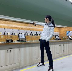 a woman standing in front of a counter pointing at something on the wall behind her