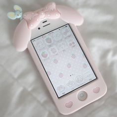 a pink cell phone sitting on top of a white bed next to a stuffed animal