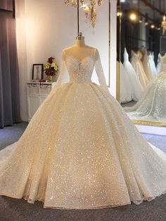 a wedding dress is displayed in front of a mirror with other dresses on display behind it