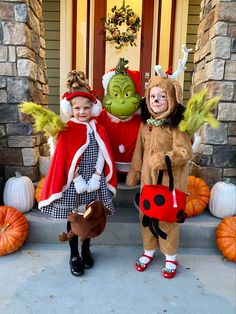 two children in costumes standing on the front porch