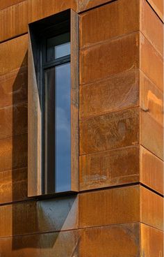 an orange brick building with a window on the side and sky in the back ground