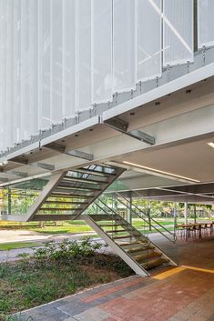 an open air building with stairs leading up to the second floor and tables on either side