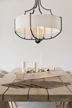 a chandelier hanging from the ceiling over a wooden table with candles on it