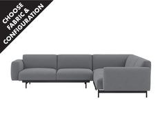 a gray sectional couch sitting on top of a white floor next to a black and white sign