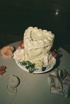 a wedding cake on a table with flowers and napkins next to the cake plate