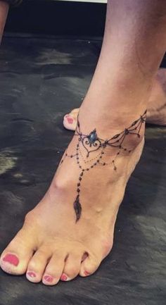 a woman's foot with a tattoo on it and beads hanging from the ankle