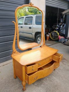 an old dresser with a mirror on it and a truck in the garage behind it