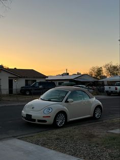 a white car parked on the side of a road at sunset or dawn in front of a house